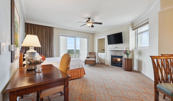 A cozy hotel room featuring a bed, television, and fireplace, perfect for guests attending the Carolina Country Music Fest 2025.