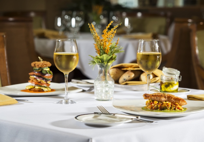 A dining table featuring two plates of food and wine glasses, ideal for enjoying meals at Marina Inn