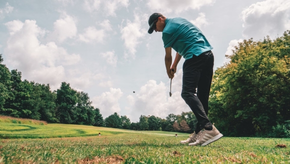 A man playing golf on a lush green field, showcasing outdoor activities at Marina Inn