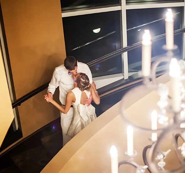 The bride and groom embrace in a kiss on the elegant stairs of a hotel, marking their special moment at Myrtle Beach, SC.