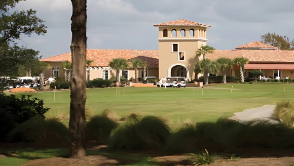 Expansive golf course with a prominent building in the background at Grande Dunes Golf.