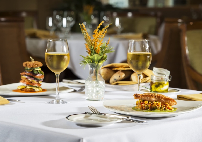 A beautifully arranged table with two plates of food and wine glasses, highlighting on-site dining at Myrtle Beach Condo Rentals.