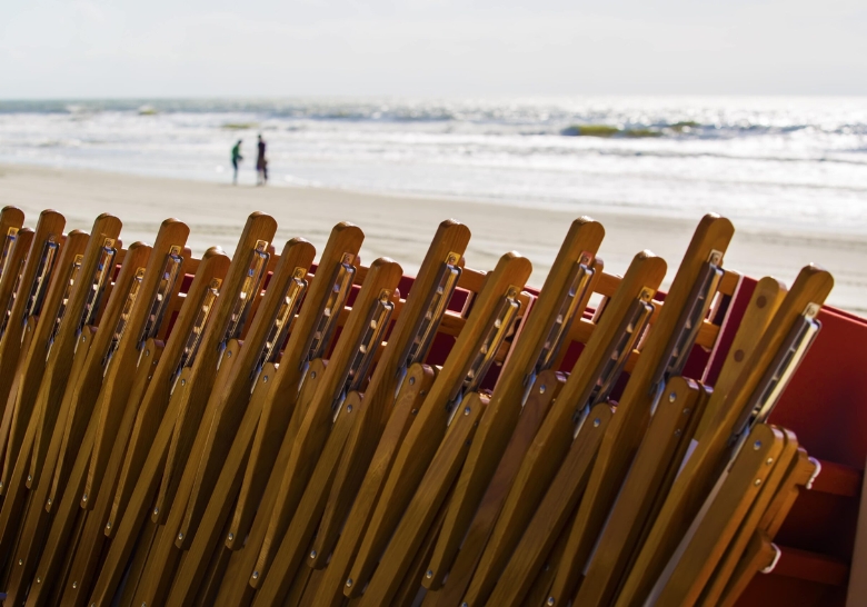 A series of wooden chairs positioned on the beach, emphasizing the exclusive access provided by Myrtle Beach Condo Rentals.