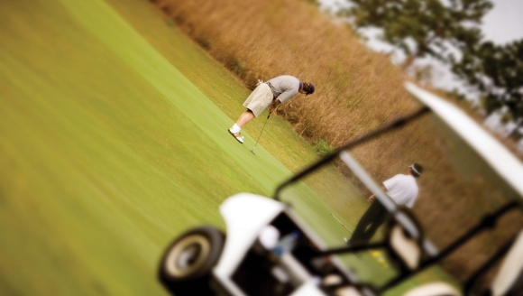 A man playing golf on a lush green field at Myrtle Beach Family Resort, enjoying a sunny day outdoors.