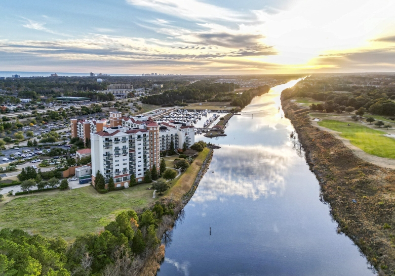 Aerial view of Marina Inn Resort at sunset, showcasing the river and surrounding buildings with vibrant colors.