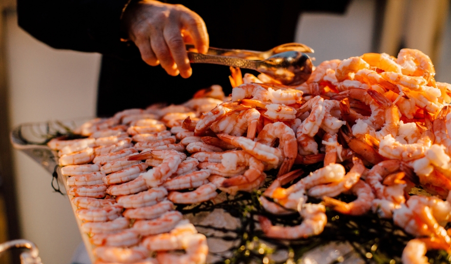 A person holds a large tray of shrimp at the Little River ShrimpFest in Myrtle Beach, showcasing a seafood festival dish.