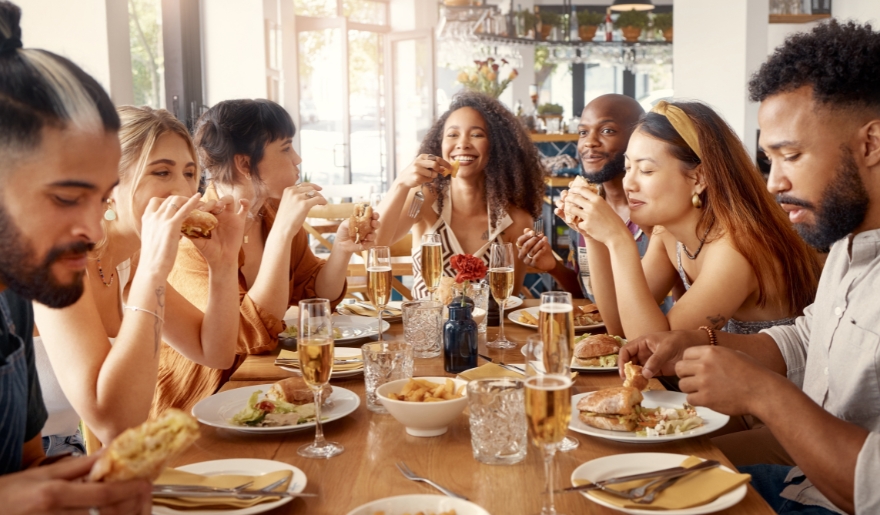 A group of people enjoying a meal together at a restaurant during the 4th of July celebration at Broadway at the Beach.