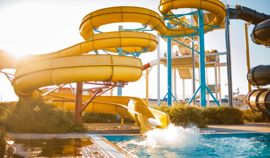 Bright yellow water slide spirals into a pool at Myrtle Waves Water Park, a popular attraction in Myrtle Beach.