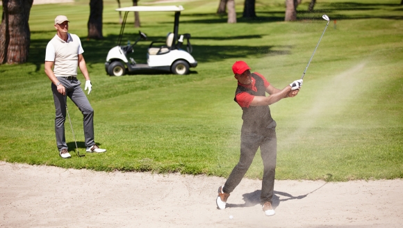 Two men enjoy a round of golf in the sand at Myrtle Beach, with championship golf courses nearby.