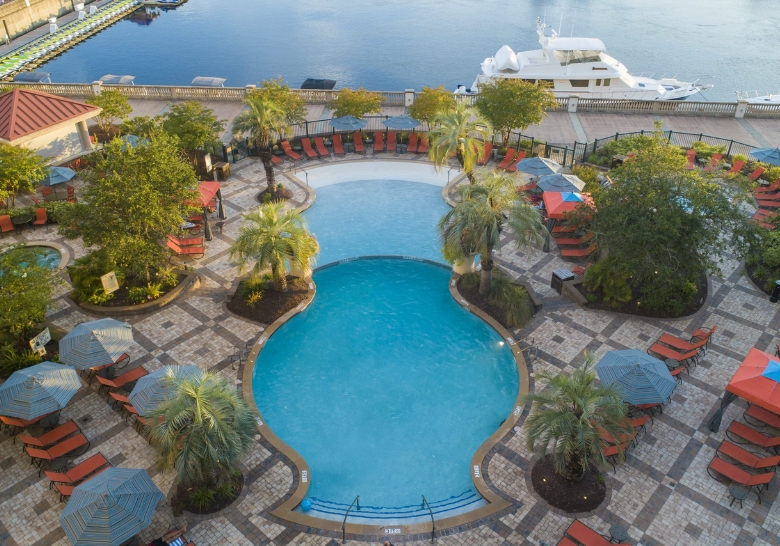 A serene pool area with lounge chairs and umbrellas, overlooking a marina, perfect for a family-friendly Easter brunch.