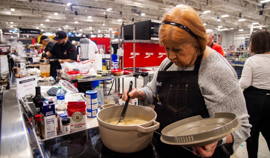 A woman in an apron prepares food in a kitchen, showcasing culinary skills for the Myrtle Beach Chili Cook-Off.