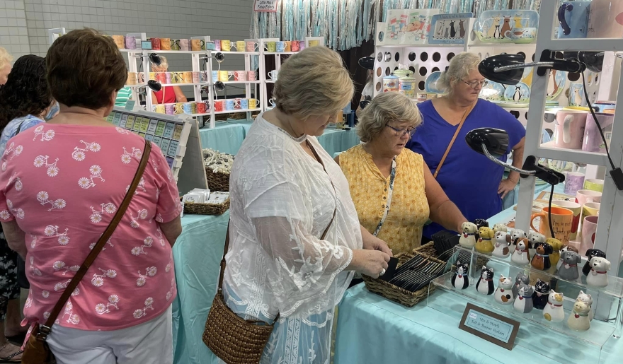 A vibrant craft fair at MCraftsmen’s Summer Classic, showcasing various handmade items and shoppers exploring the displays.