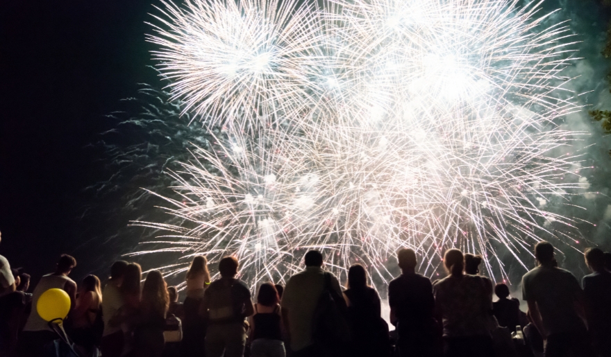 A large crowd gathers at Myrtle Beach's MarshWalk, captivated by vibrant fireworks lighting up the night sky.