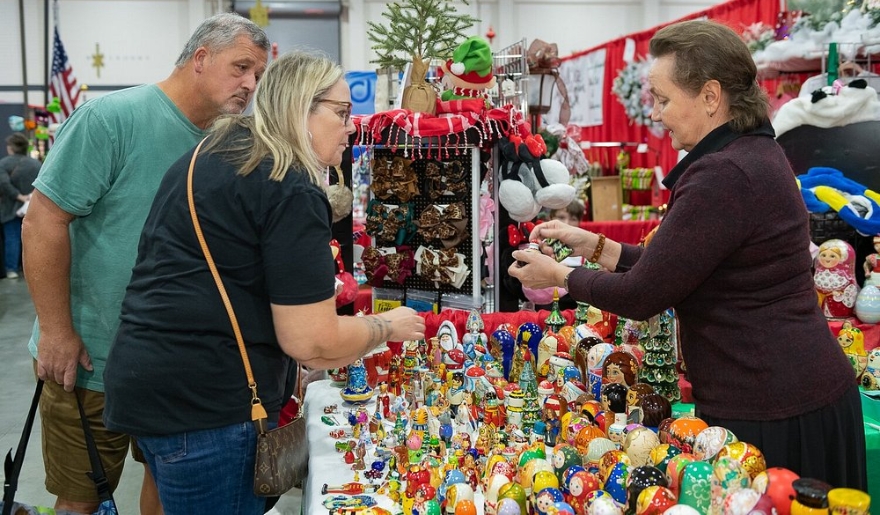 Shoppers explore a vibrant booth adorned with Christmas decorations at the Dickens Christmas Show in Myrtle Beach.