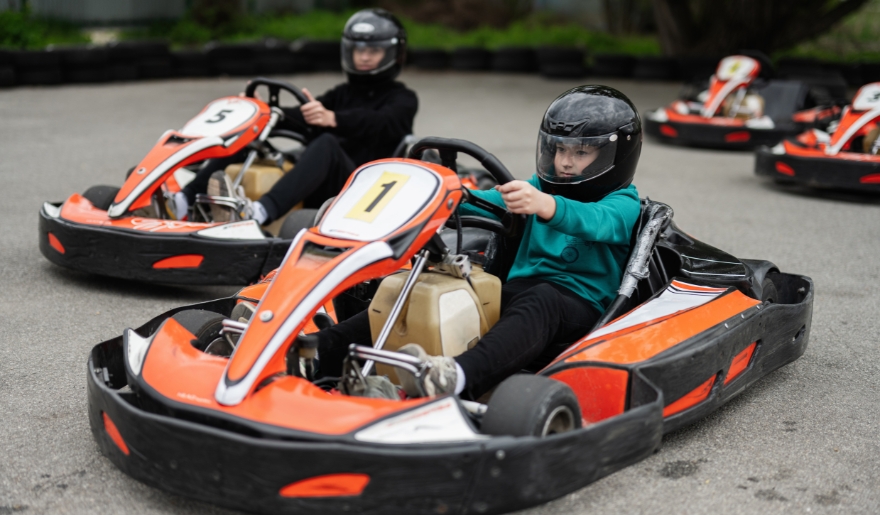Two kids in go-kart racing outfits, ready to race at The Track Family Fun Park during a Myrtle Beach family vacation.