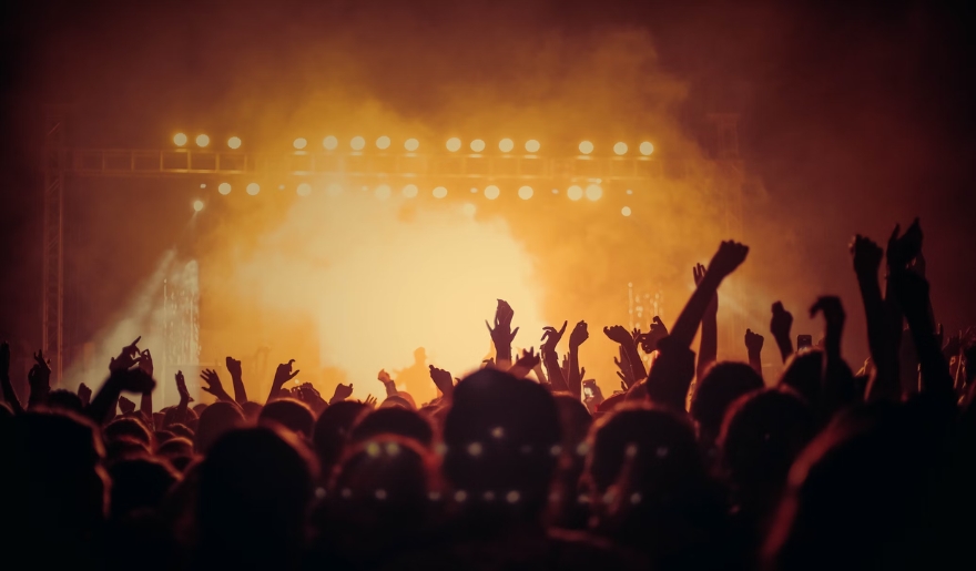 A lively crowd at Myrtle Beach's Broadway at the Beach concert, hands raised in excitement under colorful lights.