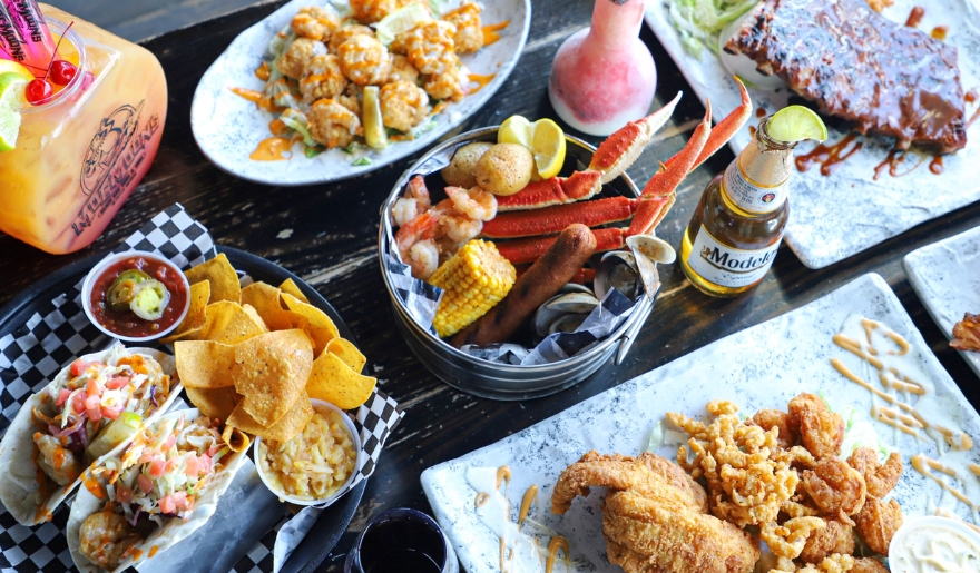 A table adorned with an array of seafood dishes and refreshing drinks, showcasing Myrtle Beach nightlife at Moe Moons.