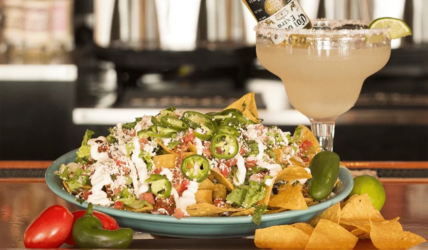 A vibrant plate of nachos with melted cheese, accompanied by a refreshing margarita, set against the lively backdrop of Myrtle Beach.