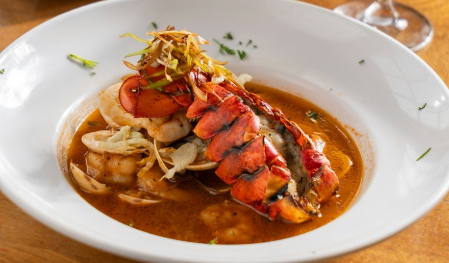 A lobster served in a bowl with sauce, showcasing a delightful dining experience at Sea Captain’s House.