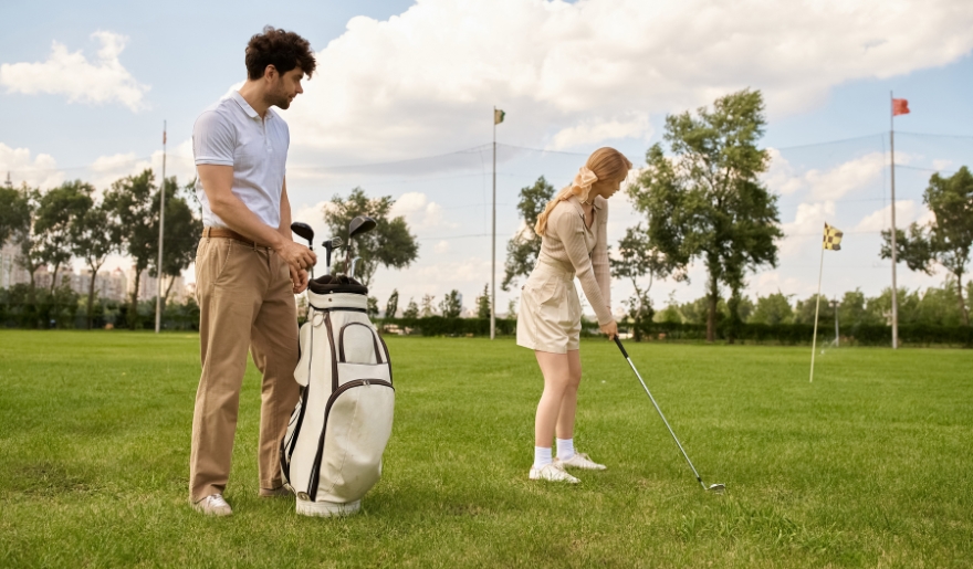 A couple on their honeymoon in Myrtle Beach stands on a golf course, ready to enjoy a round of golf together.