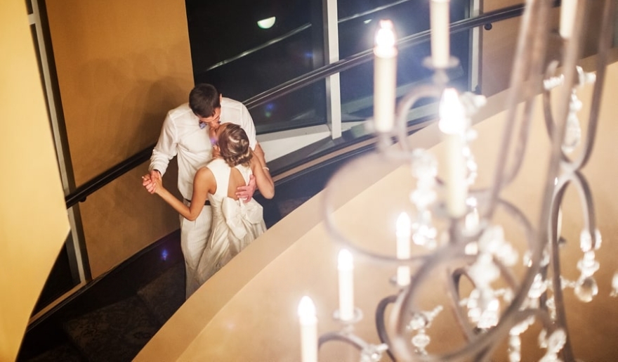 A newlywed couple kisses on the stairs of a hotel, marking their honeymoon at Marina Inn in Myrtle Beach.