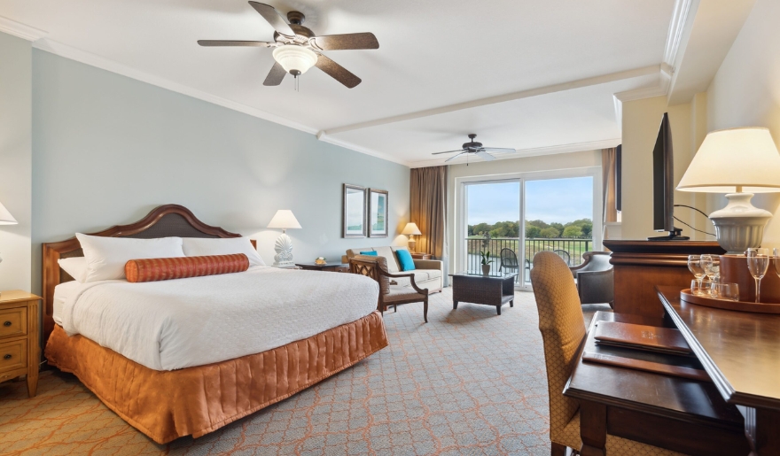 A luxurious hotel room featuring a king bed, desk, and balcony, perfect for a honeymoon at Marina Inn in Myrtle Beach.