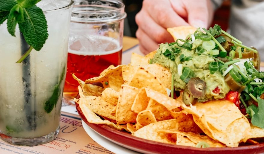 Nachos with melted cheese and toppings alongside a drink on a table, showcasing Myrtle Beach's Nacho Hippo atmosphere.