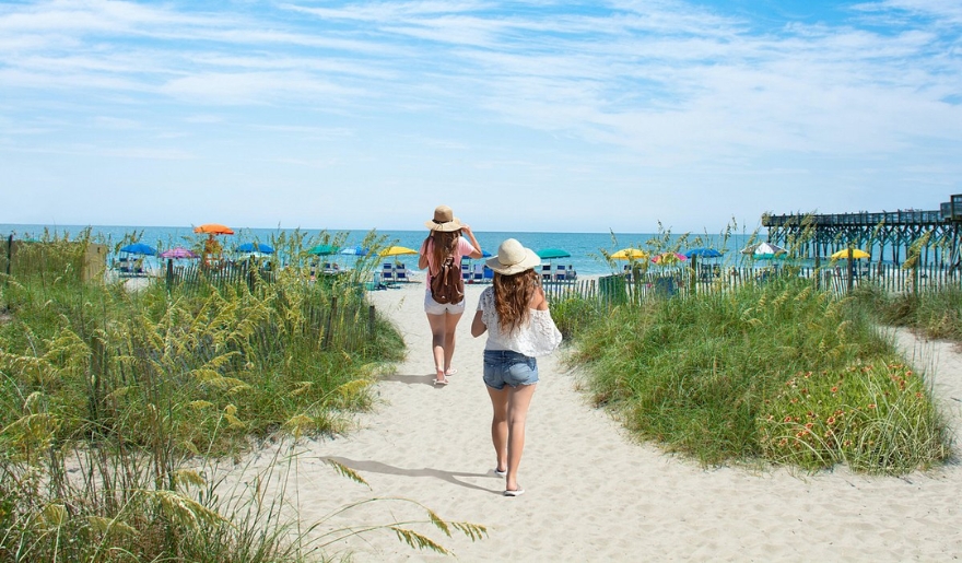 Two women walk on Myrtle Beach in September, embracing a serene and relaxing beach atmosphere.