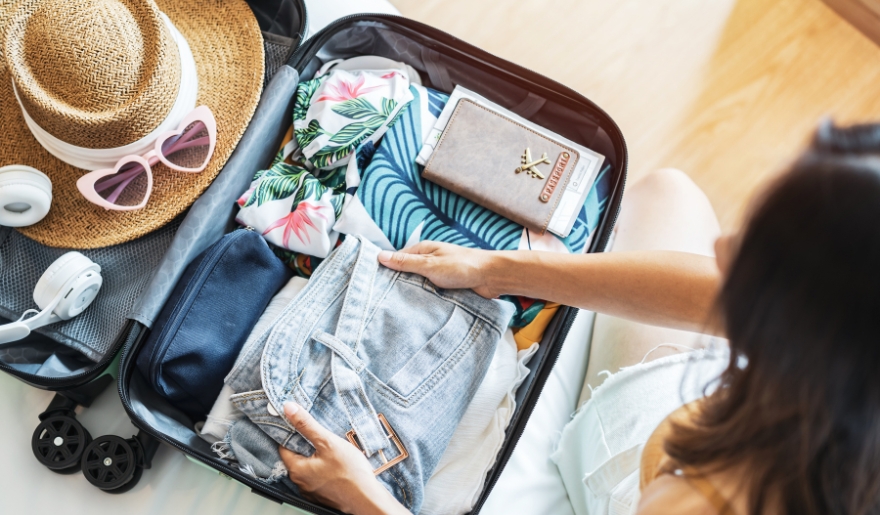 A woman is seen packing her suitcase with clothes, gearing up for a September getaway to Myrtle Beach.