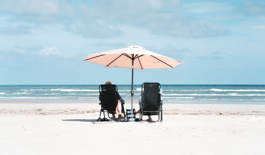 A couple sits beneath an umbrella on Myrtle Beach, soaking up the sun in September's warm weather.