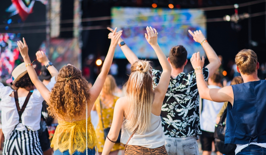 A crowd of people at a summer music festival in Myrtle Beach, all with hands up, celebrating the vibrant atmosphere.