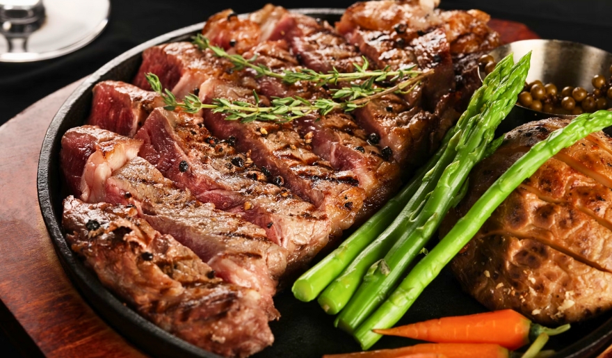 A delicious meal of steak, carrots, and asparagus served on a plate, representing summer dining options in Myrtle Beach.
