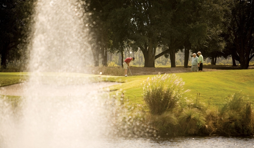 A group of people play golf near a fountain, showcasing a vibrant sporting event in Myrtle Beach.