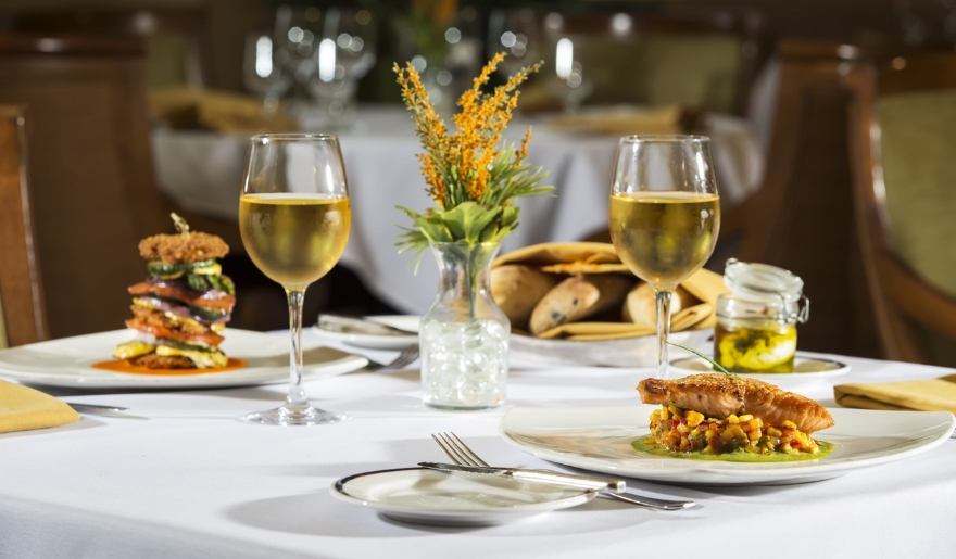 A cozy table featuring two plates of food and two glasses of wine, highlighting an evening at Marina Inn in Myrtle Beach.