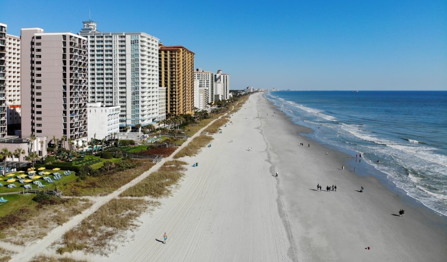Myrtle Beach in August featuring tall buildings alongside a sandy beach, inviting for a fun beach day.
