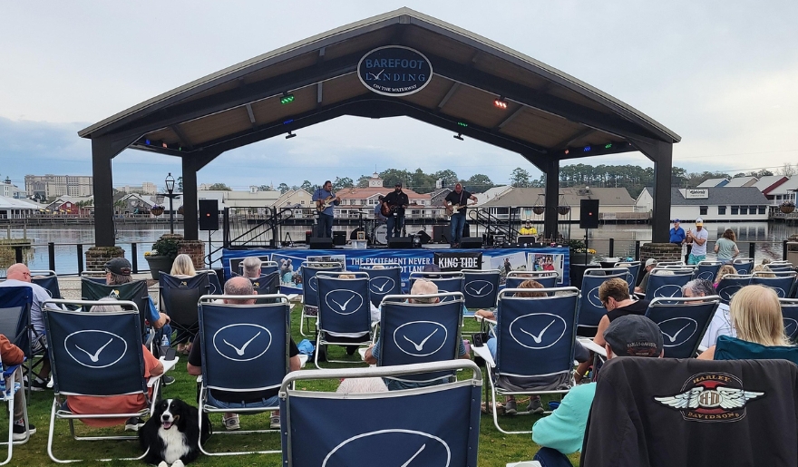 A crowd of people in lawn chairs enjoying a concert at Barefoot Landing, Myrtle Beach, during August's live music scene.