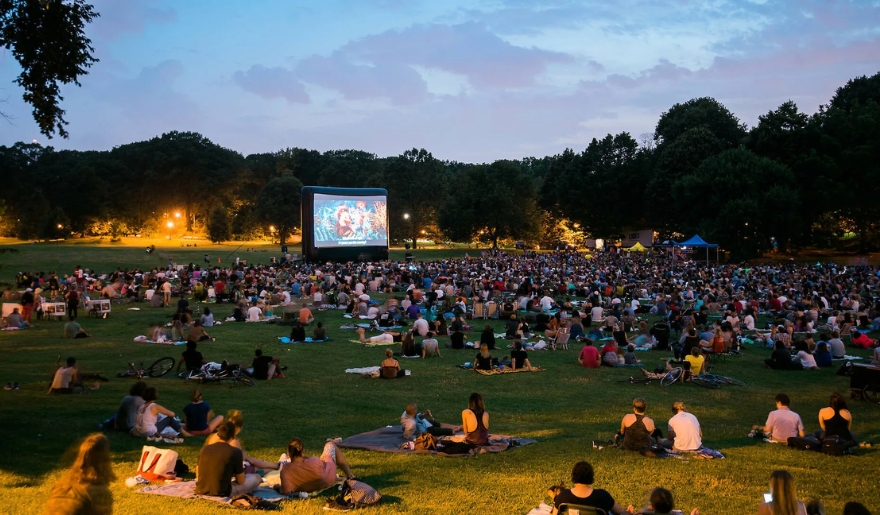 People enjoy a movie screening on a grassy field at Valor Park, Myrtle Beach, during the August Movie Under the Stars event.