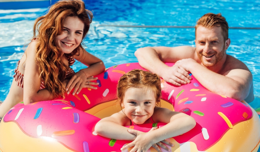A joyful family spends a summer day at Myrtle Waves Waterpark, swimming and playing together in the pool.