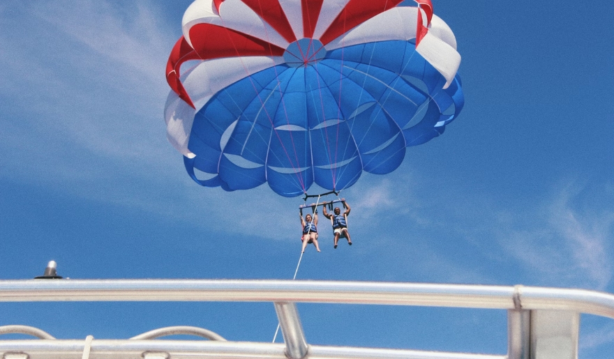 A person parasails against a clear blue sky over Myrtle Beach, capturing the essence of summer water sports in June.