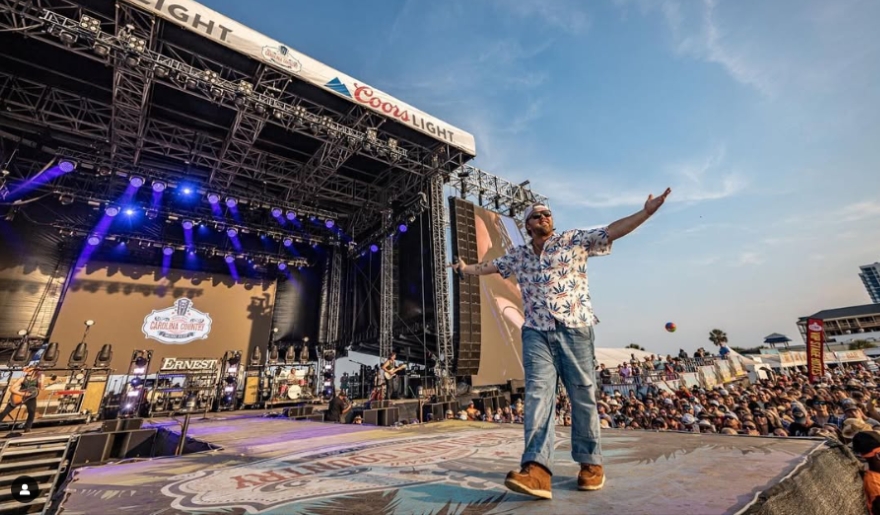 A man stands on stage at the Carolina Country Music Fest in Myrtle Beach, June, with arms outstretched to the audience.