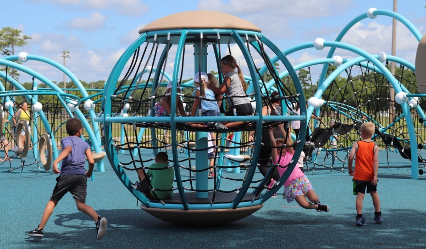 A group of children plays on a playground at Myrtle Beach, surrounded by summer fun in June.