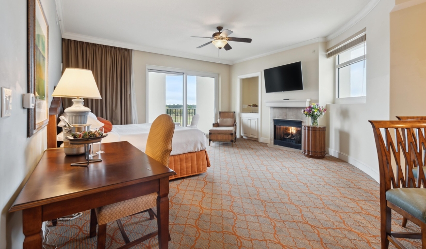 A cozy room at Marina Inn with a king bed, desk, television, and fireplace, set in Myrtle Beach during June.