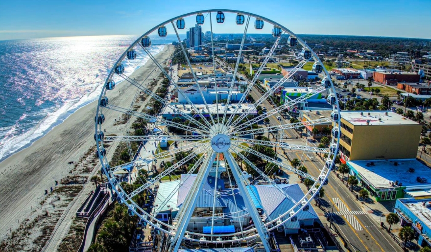 Myrtle Beach, SC in June with the iconic SkyWheel, highlighting the lively beach environment and clear skies.