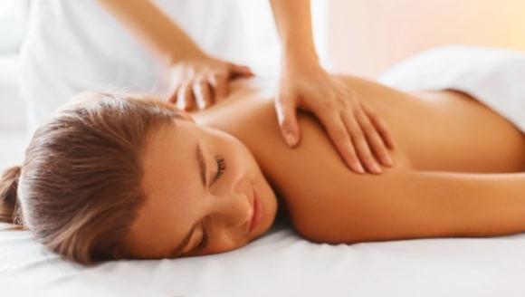 A woman enjoys a relaxing back massage at a spa, part of a birthday party venue in Myrtle Beach, SC.