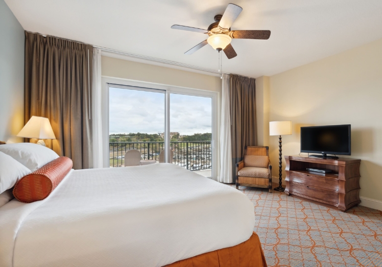 Cozy hotel room featuring a bed, television, and balcony, ideal for honeymooners in a quiet Myrtle Beach location.