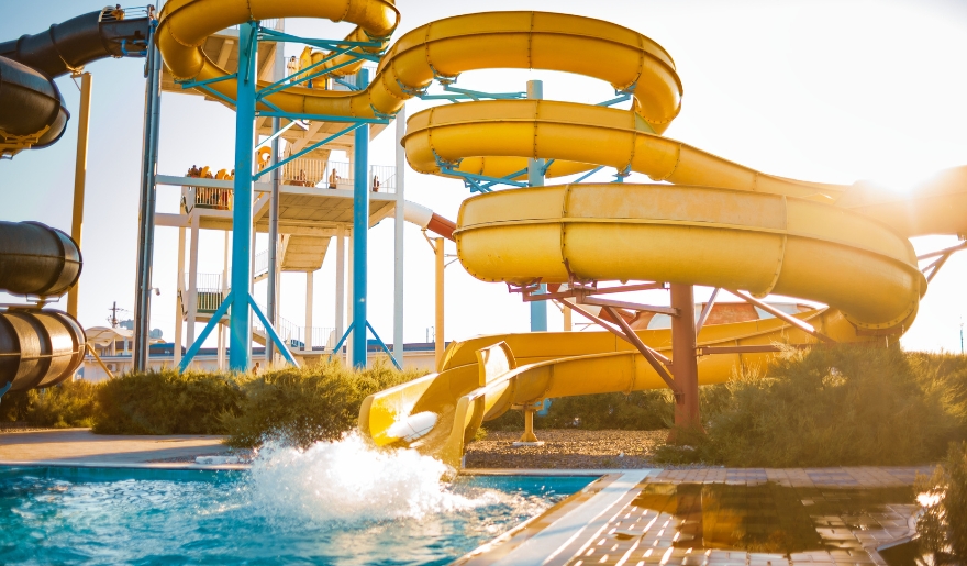 A large yellow water slide towers over a pool, featured in the Myrtle Beach itinerary for the afternoon.
