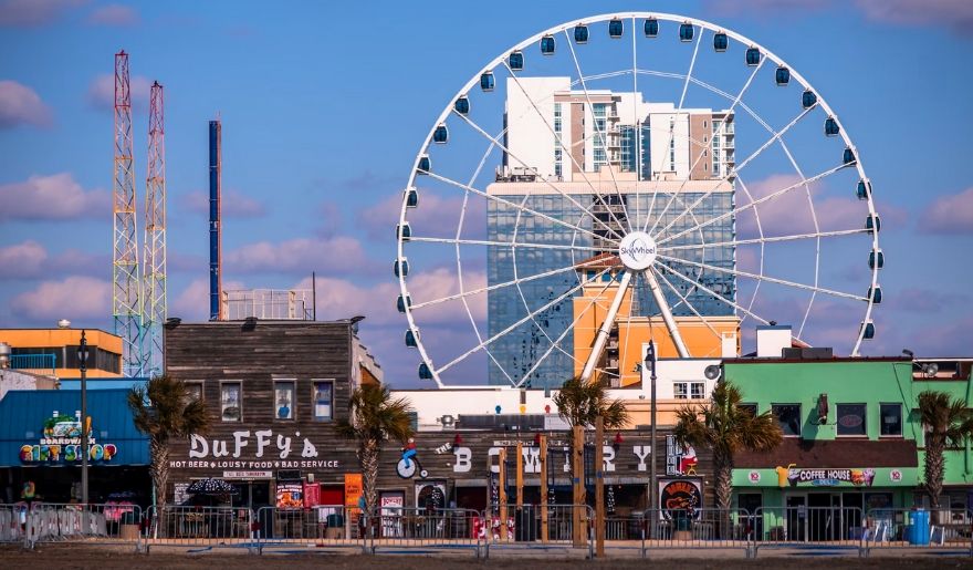 The image shows a ferris wheel located in front of a building, featured in the Myrtle Beach afternoon itinerary.