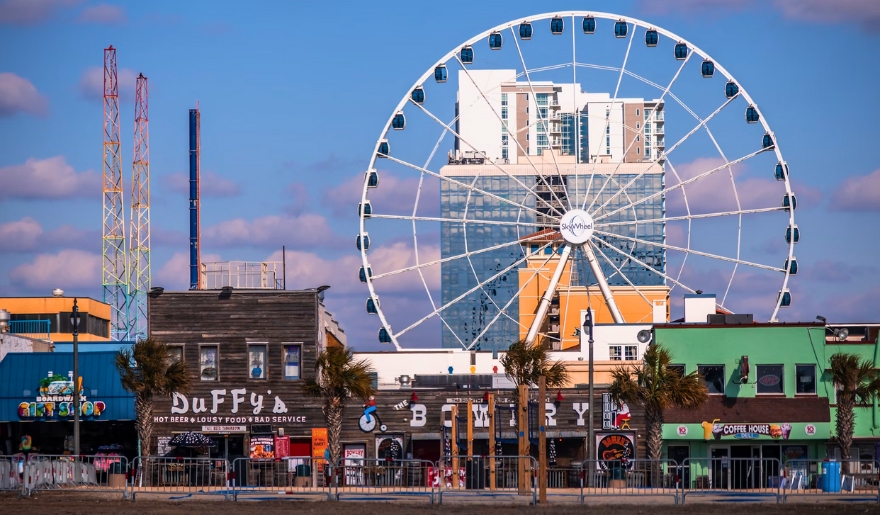 The image shows a ferris wheel located in front of a building, featured in the Myrtle Beach afternoon itinerary.