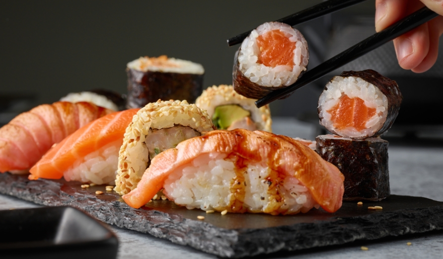 A person holding chopsticks above a plate of sushi, part of an evening itinerary in Myrtle Beach.