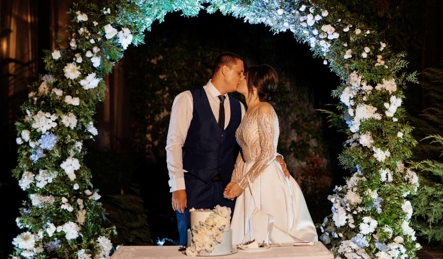 A bride and groom share a kiss beneath a floral arch at The Cinderella House wedding chapel in Myrtle Beach, SC.